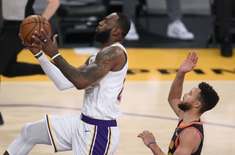 LOS ANGELES, CALIFORNIA - FEBRUARY 28: LeBron James #23 of the Los Angeles Lakers scores on a layup past Stephen Curry #30 of the Golden State Warriors during the second quarter at Staples Center on February 28, 2021 in Los Angeles, California. (Photo by Harry How/Getty Images) NOTE TO USER: User expressly acknowledges and agrees that, by downloading and/or using this Photograph, user is co<em></em>nsenting to the terms and co<em></em>nditions of the Getty Images License Agreement. Mandatory Copyright Notice: Copyright 2021 NBAE.