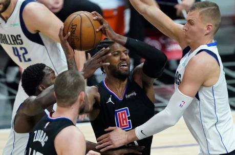 May 25, 2021; Los Angeles, California, USA; LA Clippers guard Paul George (center) is defended by Dallas Mavericks forward Dorian Finney-Smith (left) and center Kristaps Porzingis (right) during the third quarter of game two in the first round of the 2021 NBA Playoffs at Staples Center. Mandatory Credit: Robert Hanashiro-USA TODAY Sports