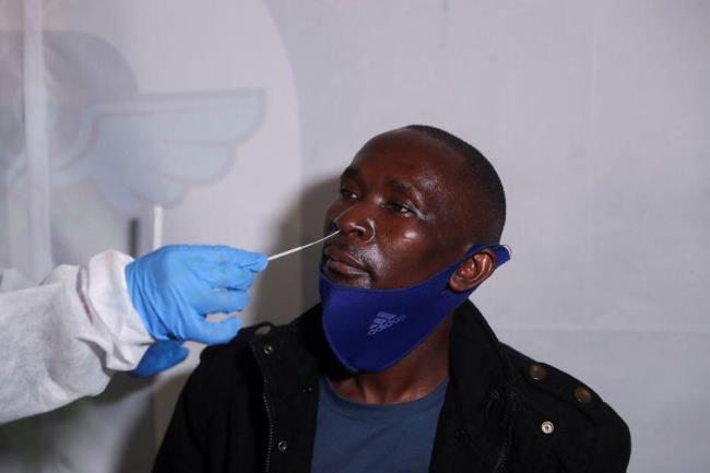 A healthcare worker collects a swab from a passenger for a PCR test against the coro<em></em>navirus disease (COVID-19) before traveling to Uganda, amidst the spread of the new SARS-CoV-2 variant Omicron, at O.R. Tambo Internatio<em></em>nal Airport in Johannesburg