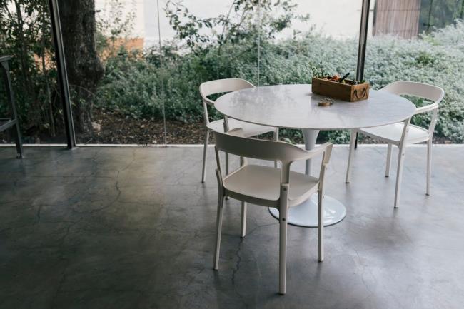 Modern Farmhouse Glass Kitchen With Three Plastic Chairs And Table On Co<em></em>ncrete Flooring