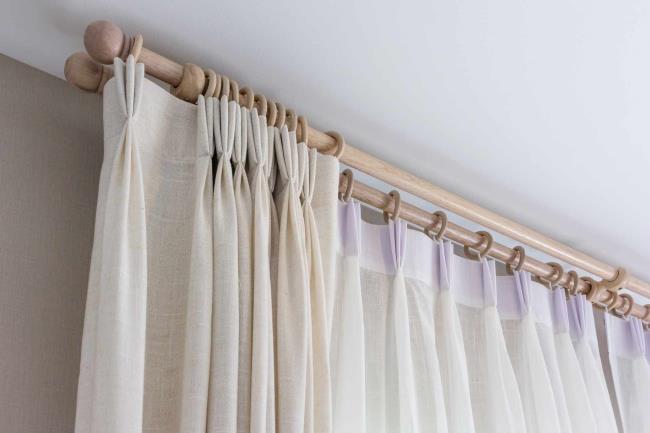 Wooden curtain rods and rings with cream-colored curtain haning