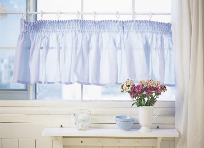 Thin blue fabric window tier curtain hanging on white rod