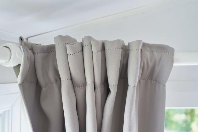 Light gray rod-pocket curtain on white rod closeup