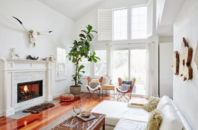 White living room with bright windows covered with shutters, blinds and curtains