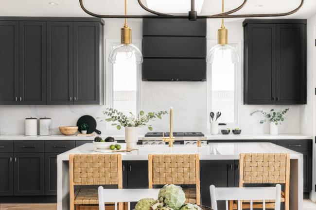 Kitchen with black cabinets and white island with natural woven chairs