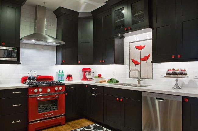 Retro black kitchen with red accents and hardware and stainless steel appliances