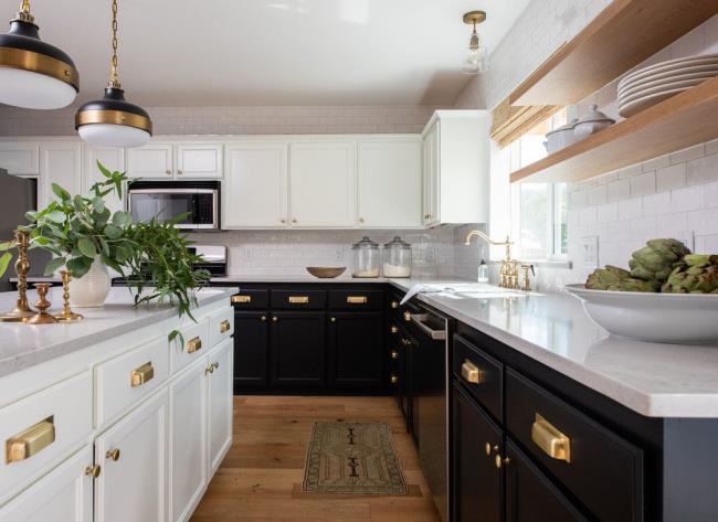 Black and white kitchen cabinets with white tile, wood accents, and me<em></em>tallic hardware