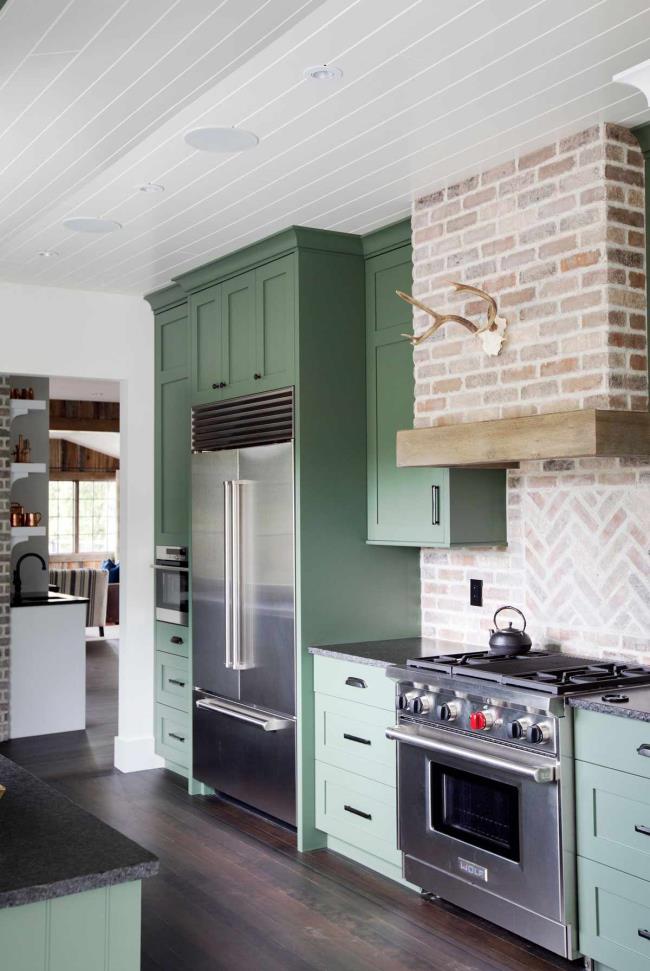 Green kitchen cabinets with brick backsplash