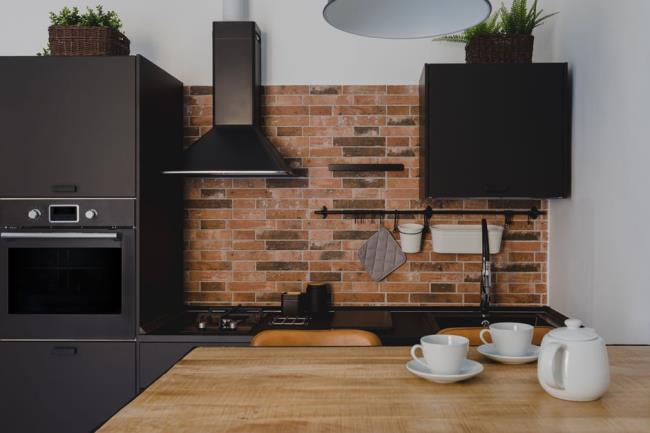 Black stainless steel appliances in brick walled kitchen