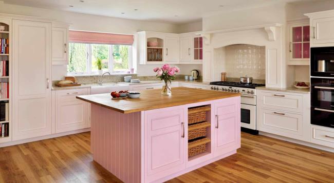 pink and white kitchen with wood flooring, island countertop, and accents