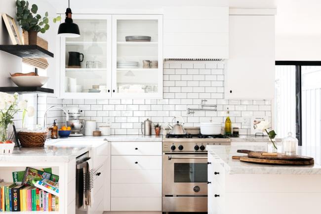 Modern white kitchen decorated with brick wall behind stainless steel oven 