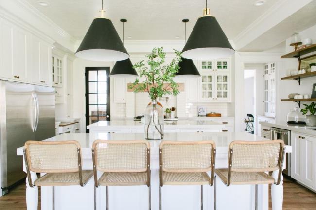 white kitchen cabinets, basket chairs, and green pendant lamp