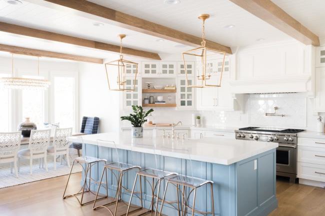 white kitchen with wooden beams, light blue island, and copper and gold accents