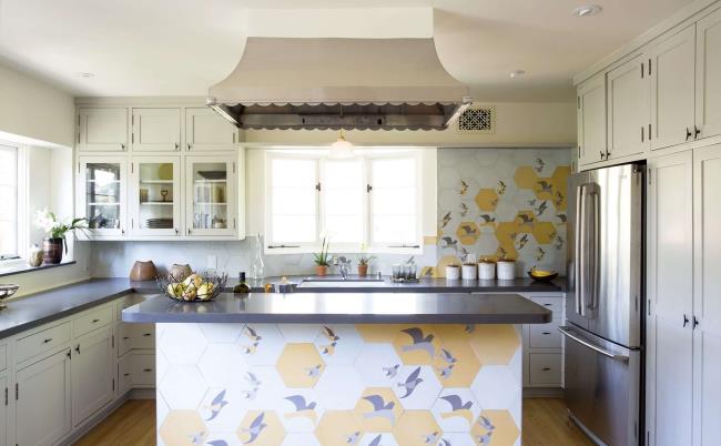 Tile of birds adorning a white kitchen with stainless steel appliances.