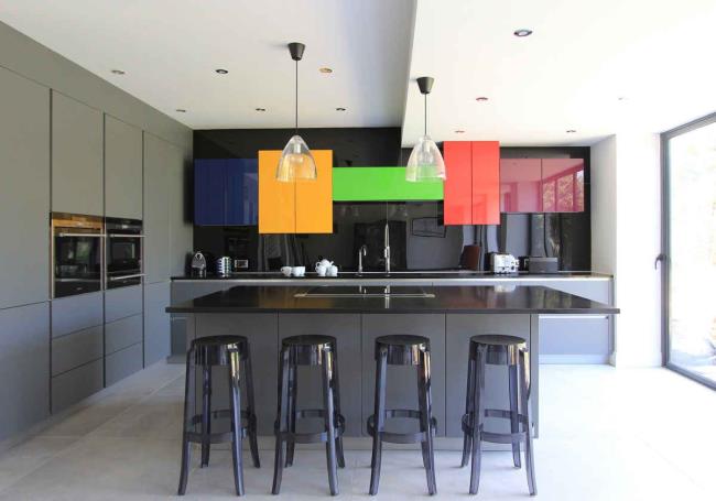 Bright kitchen cabinets with black countertop and four chairs.