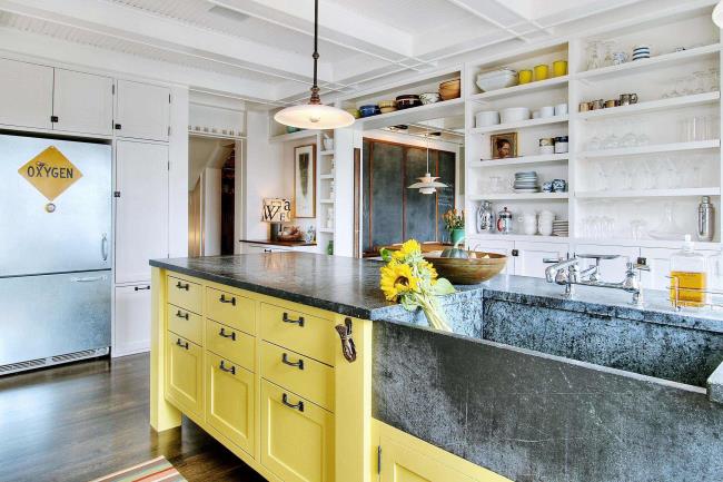 Soapstone kitchen sink with yellow cabinets.