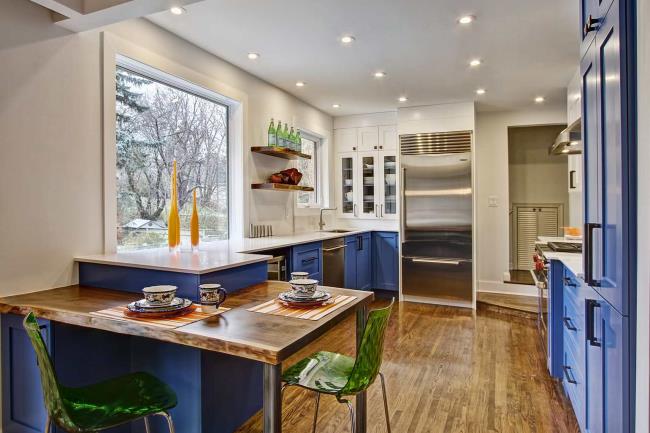 Blue-and-green kitchen with blue cabinets and wood flooring.