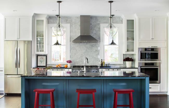 White kitchen with blue cabinets and three red stools.