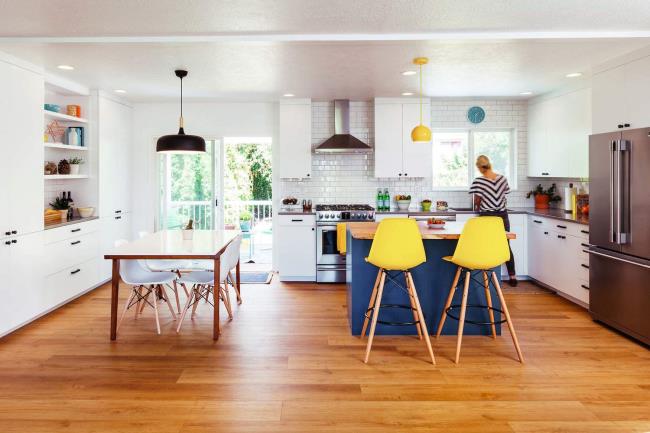 Orange pendant lights, blue chairs, and white countertops in a kitchen.