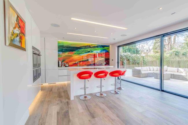 Multicolored kitchen backsplash with orange stools.