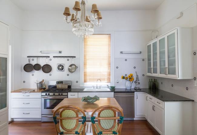 Shabby chic New Orleans kitchen with chandelier light and pots hanging on the wall.