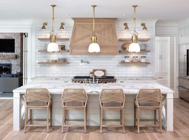 Neutral and crisp french country kitchen with four wicker chairs and three hanging pendant lights over island.