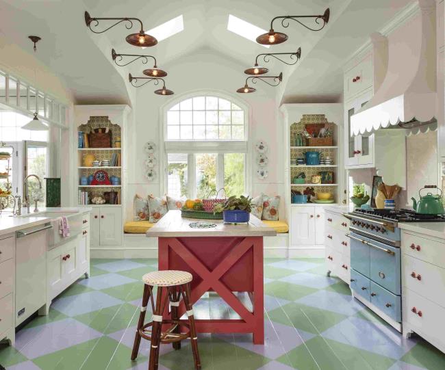 Bold French country kitchen with red island, blue stove, and green and white floor.