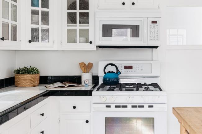 Modern kitchen with all white cabinets and appliances with light decor on black and white sqaure tiles