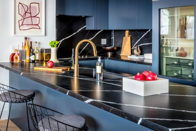 Black-and-blue kitchen with black marble-like countertops.