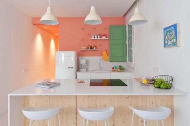 White countertops with a salmon-color accent wall in a white kitchen.