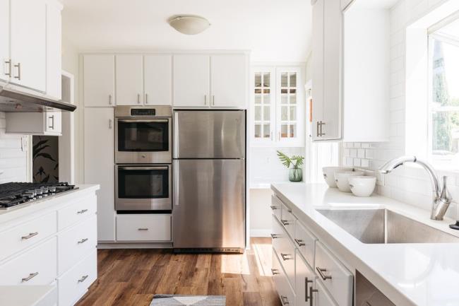 Brightly-lit kitchen with quartz countertops and white cabinets and stainless steel appliances