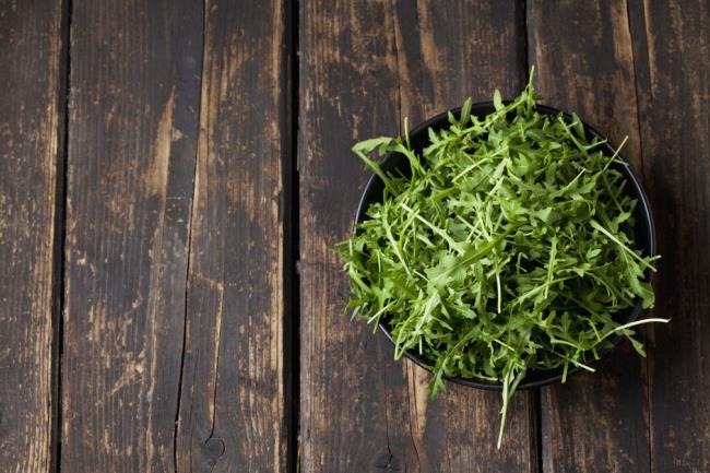 arugula in a pot on a wooden background