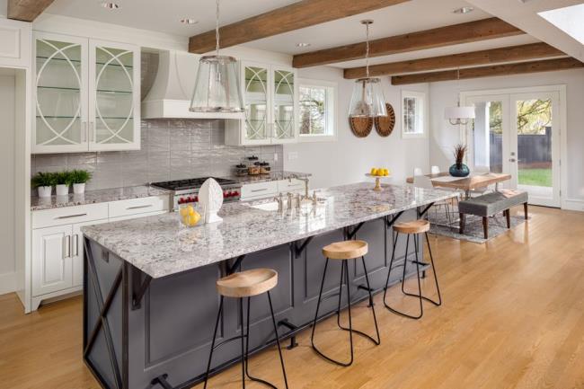 beautiful kitchen with lights off in new luxury home with island, pendant lights, and glass fro<em></em>nted cabinets, and view of dining room