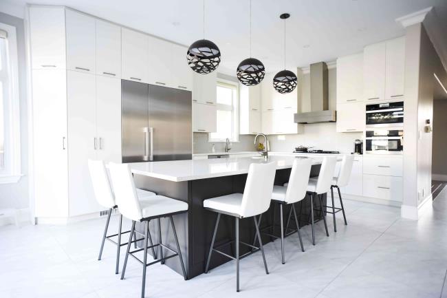 Modern white kitchen with large island and stainless steel appliances.