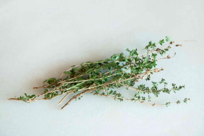 Summer savory herb stems lying in a stack on white surface