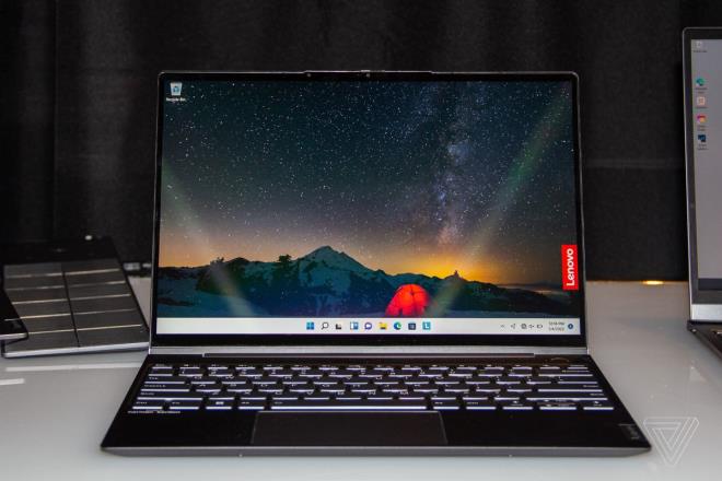 The ThinkBook 13X open on a white table. The screen displays an outdoor night scene with a red tent in the middle and the Lenovo logo on the right side.